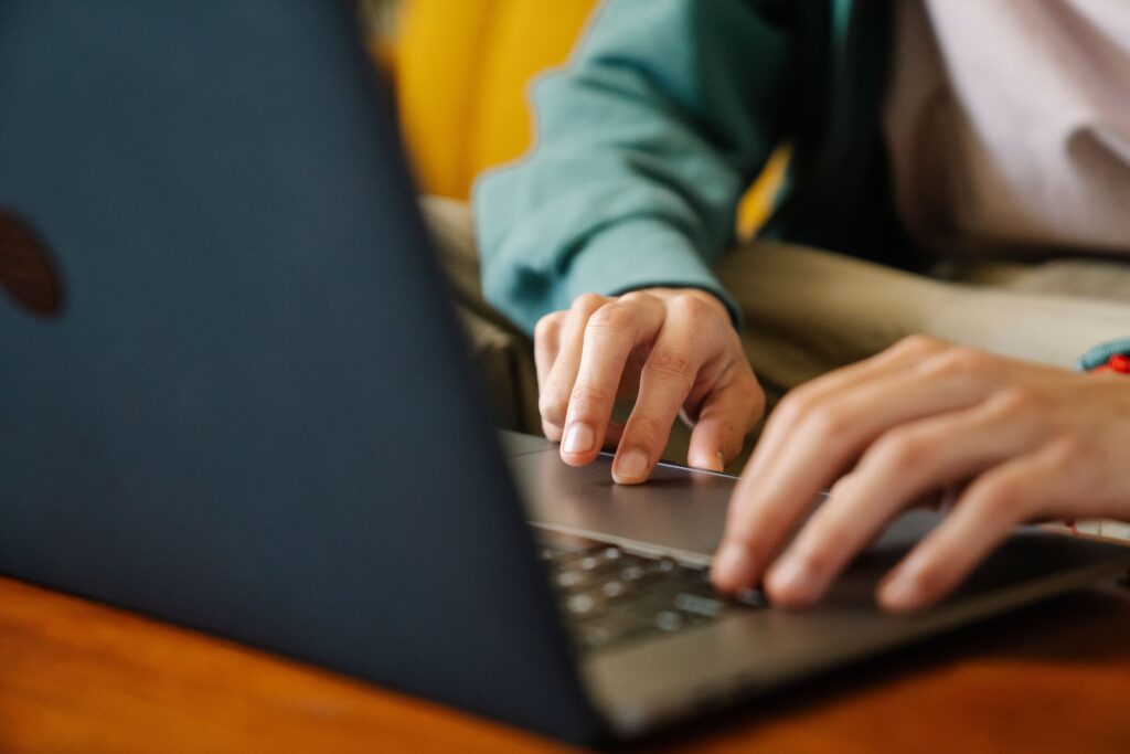 A person typing on a laptop with a confused expression.